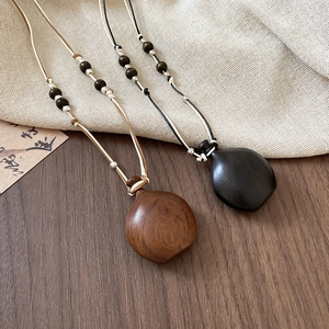 Detail of wooden water-drop pendants on woven cords with natural beads in ethnic style