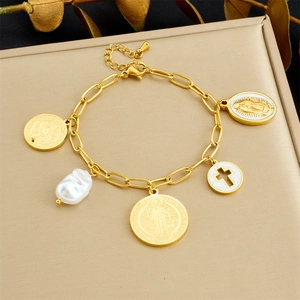 Detail of gold-plated chain bracelet with white enamel cross and vintage coin charms