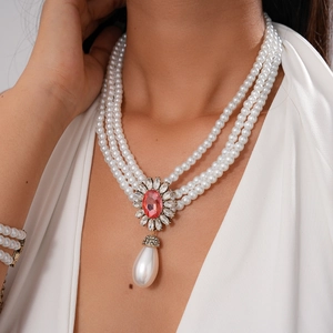 Macro detail of multi-layer pearl necklace with vintage floral stone pendant and drop pearl