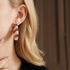 Retro geometric resin and wood earrings with striped design worn by a model