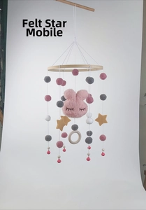 Detail of felt stars and plush balls hanging from a wooden ring on a baby mobile