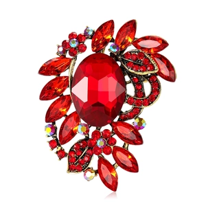 Elegant vintage gold alloy brooch with red oval glass stone and leaf-shaped crystals