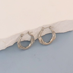 Detailed macro shot of silver geometric twisted earrings on a textured stone base