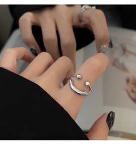 Detail of silver double-layered smiley face ring worn on model with black nails