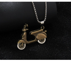 Close-up of vintage bronze motorcycle pendant with silver chain on textured background