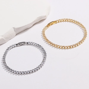 Detail von Gold- und Silber-Tennisarmbändern mit Zirkonia auf weißem Naturstein