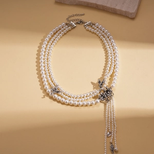 Detail of layered pearl necklace with silver angel charms and long feather tassels