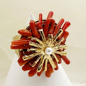 Gold coral-shaped statement ring with white pearl and red accents on a display stand