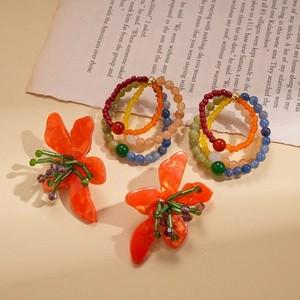 Close-up of colorful resin flower earrings and beaded hoops on vintage book pages