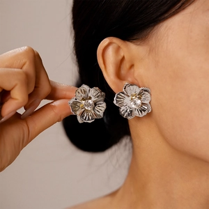 Gros plan sur une boucle d'oreille fleur argentée texturée avec cristal brillant