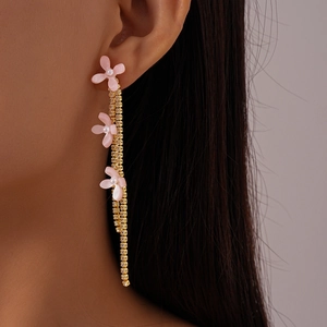 Detail of long tassel earrings with pink flowers, gold chains and sparkling crystals
