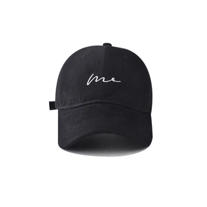 Detailed close-up of white 'me' embroidery on a black cotton twill baseball cap