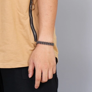Gros plan d'un bracelet gourmette rétro gris foncé en acier sur un poignet masculin