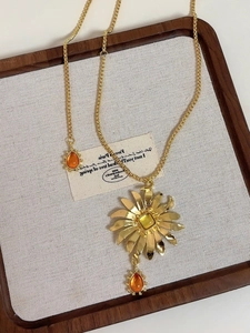 Detail of vintage gold flower pendant necklace with amber gemstone on a wooden tray