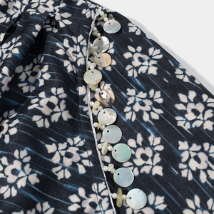 Détail du tissu imprimé bleu foncé avec des perles blanches et franges de coquillages