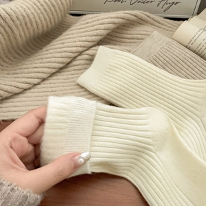 Detail view of cream white ribbed wool socks with folded cuffs for autumn and winter