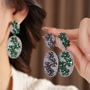 Macro detail of vintage floral oval earrings with purple and green zircon stone inlay