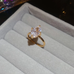 Close-up of oval zircon ring with four-prong setting on gray velvet jewelry box