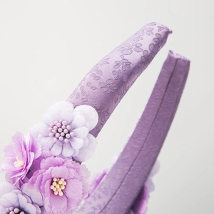 Fashionable purple floral headband featuring textured satin fabric and layered fabric flowers