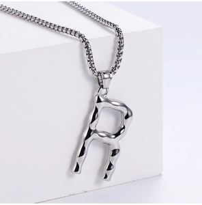 Detail of silver letter R pendant with lava texture and stainless steel box chain