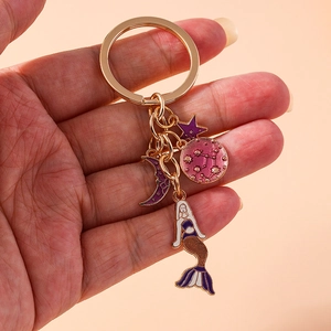 Detailed close-up of a gold mermaid keychain with celestial star and moon pendants