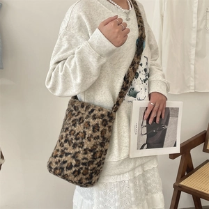 Detail of leopard print plush bucket bag with cylindrical design on fashion model