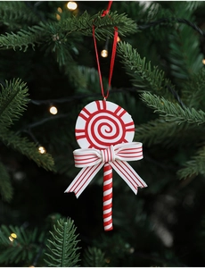 Macro shot of red and white striped candy cane ornament with bow on Christmas tree