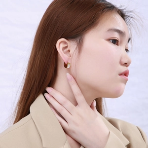 Gros plan d'une femme portant les boucles d'oreilles créoles dorées avec détails nacrés