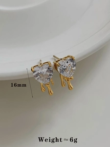 Close-up of heart-shaped zircon earrings with golden melting metal drip details