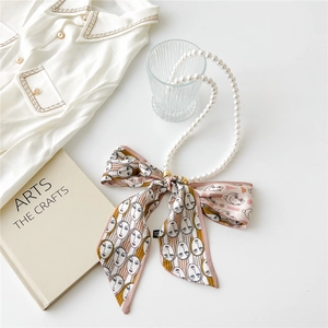 Detail of pink silk scarf necklace with art face pattern and elegant white pearls