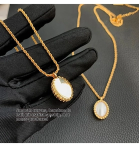 Detailed macro view of gold plated necklace with oval white shell pendant and textured rim