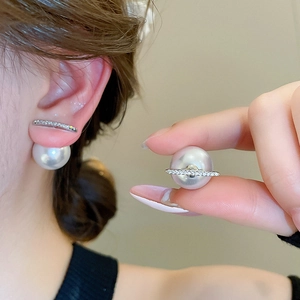 Detail view of silver pearl earrings featuring a curved rhinestone bar and double pearl design