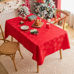 Festive red tablecloth with snowflake patterns set on a Christmas dinner table with decor