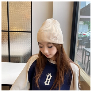 Detail view of a beige ribbed knit beanie worn outdoors for winter warmth.