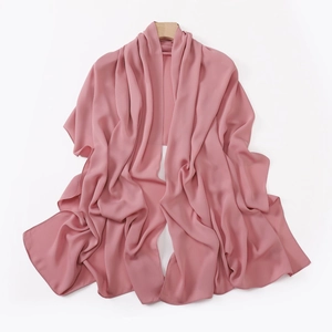 Close-up of pink silk-feel scarf with soft texture and elegant drape on wooden hanger