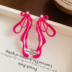 Detail of rose pink ribbon bow earring with a sparkling rhinestone on white card