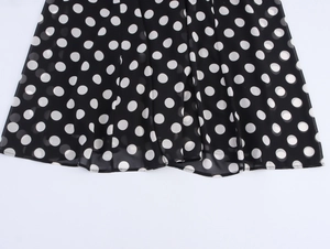 Close-up of black chiffon dress hem featuring white polka dots and delicate pleats