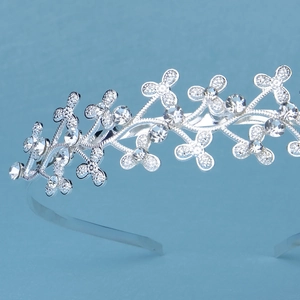 Macro shot of silver rhinestone crown headband featuring floral and leaf metal details