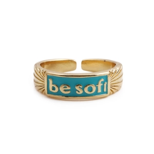 Detail view of gold-plated ring featuring teal enamel and 'be soft' engraved lettering
