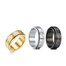 Detailed view of three rotating stainless steel rings with Greek key pattern in gold, silver, black