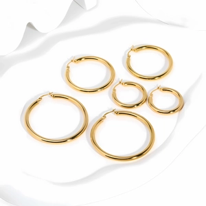 Three pairs of 18K gold plated stainless steel hoop earrings in varying sizes on a white wave background