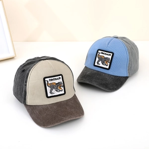 Detailed close-up of color-block kids baseball caps featuring dinosaur embroidery patches