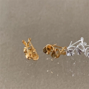 Macro detail of minimalist heart stud earrings in polished gold and silver 925 sterling steel