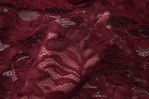 Dettaglio del pizzo bordeaux elegante con trama floreale delicata sulla pelle nuda