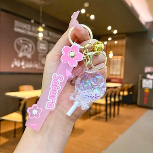Detail of Sakura keychain featuring pink silicone strap, star glitter lollipop, and bell