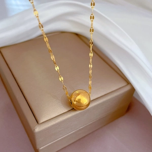 Close-up of golden titanium steel ball pendant necklace on a jewelry box and silk