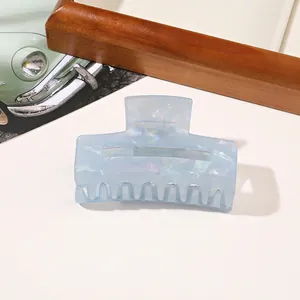 Close-up of a large rectangular hair claw clip with a pearlescent light blue shell texture