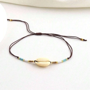 Detail of adjustable woven cord bracelet featuring a natural shell and evil eye beads