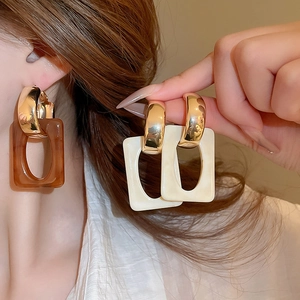 Detail view of rectangular resin drop earrings in amber and cream white geometric style