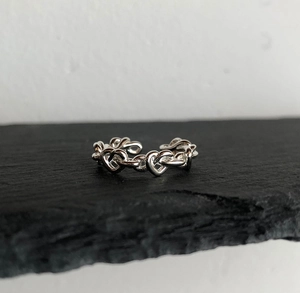 Macro shot of silver heart-shaped linked chain open ring on a textured black stone